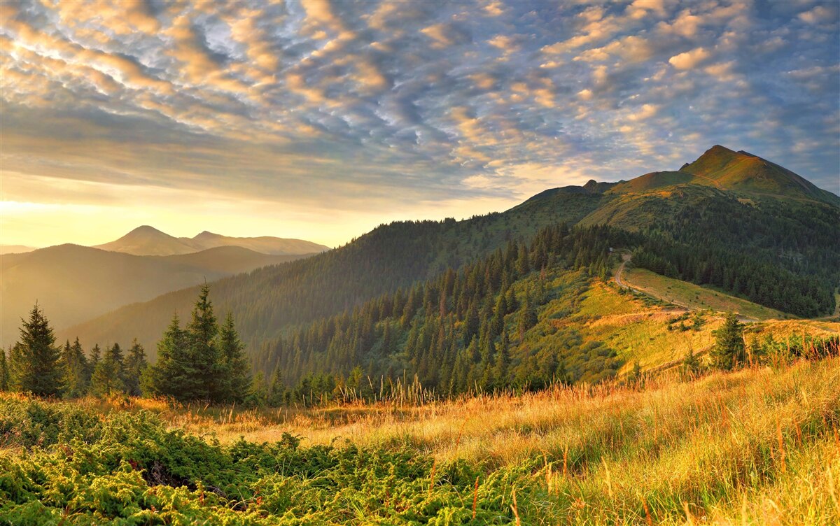 Fototapeten warmer Sonnenuntergang über den Bergen in den Wolken