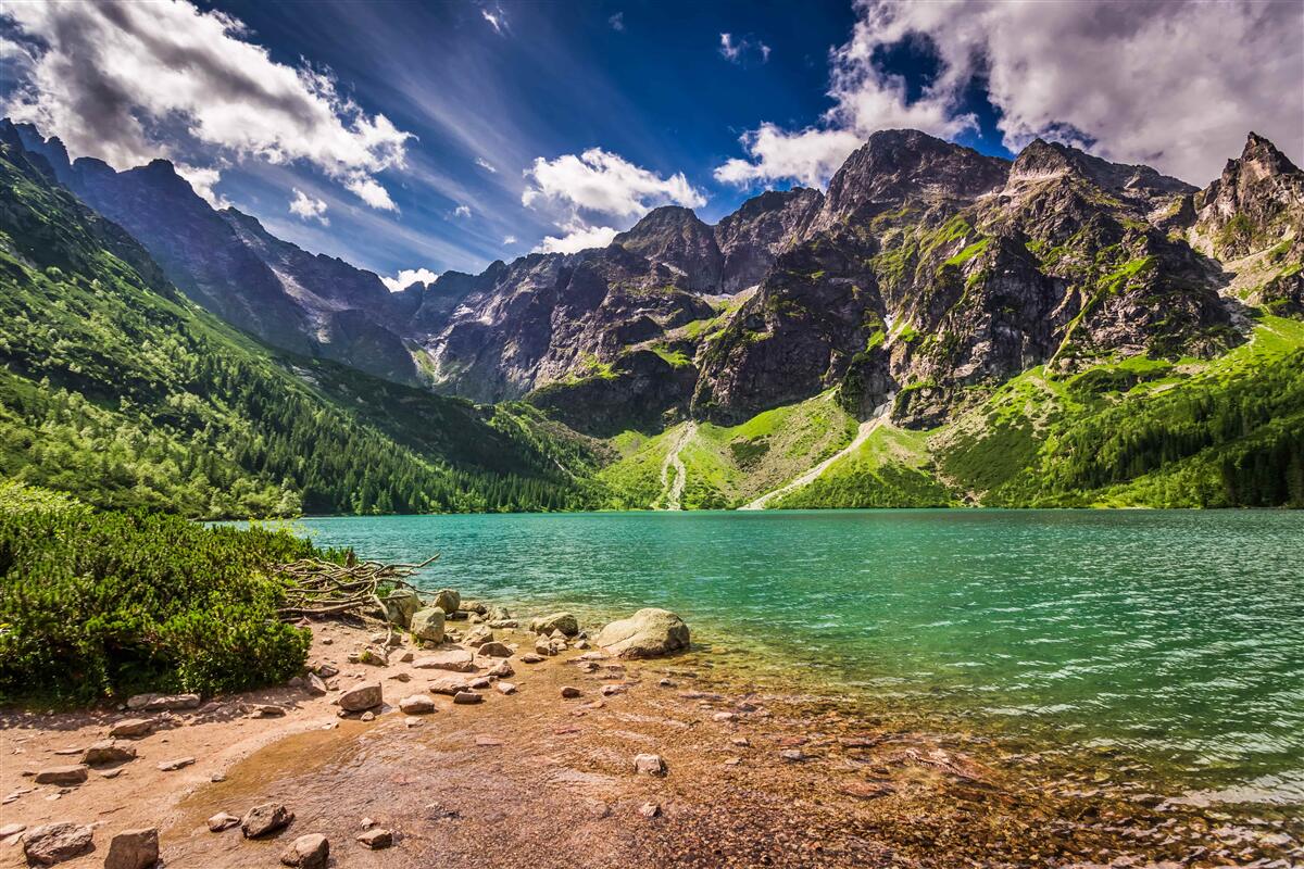 Fototapeten Berge in der Nähe eines grünen Sees an einem Sommertag